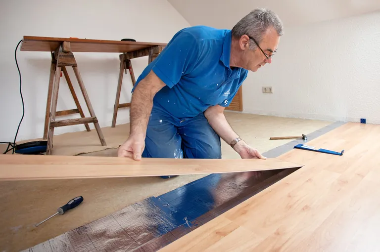 Handwerker verlegt Parkettboden.