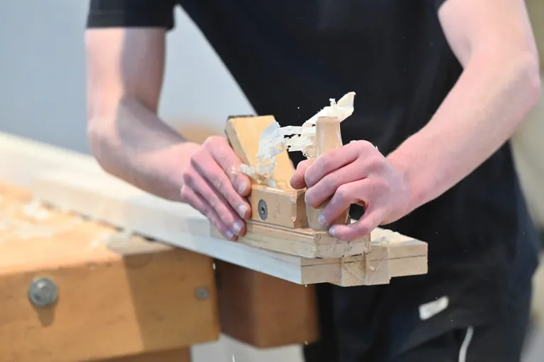 Schreiner-Azubi schleift Holz.