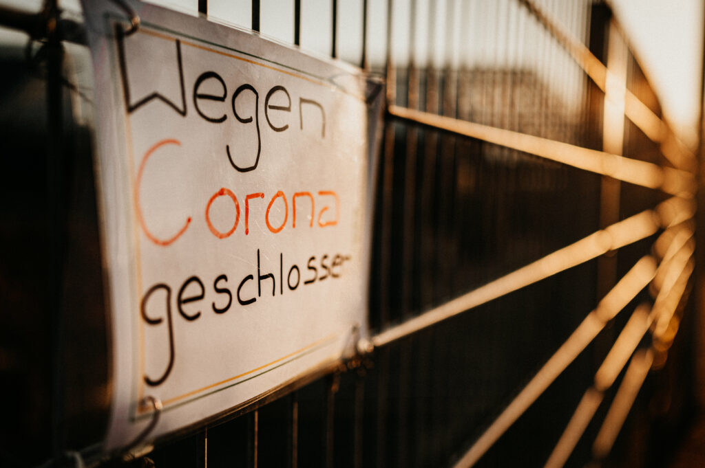 Schild wegen Corona geschlossen am Zaun eines Betriebsgeländes