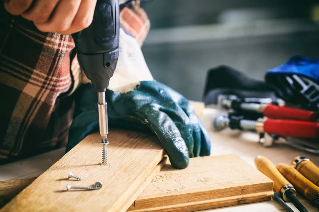 Handwerker bohrt mit Maschine in Holz.