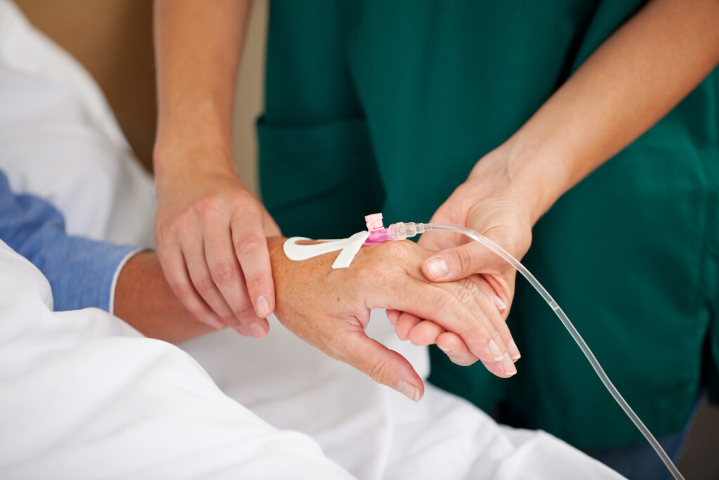 Krankenpflegerin hält Arm einer Patientin