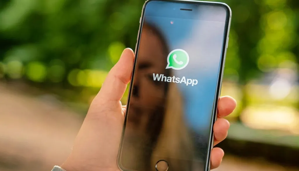 Frau hält Handy mit Whatsapp in der Hand
