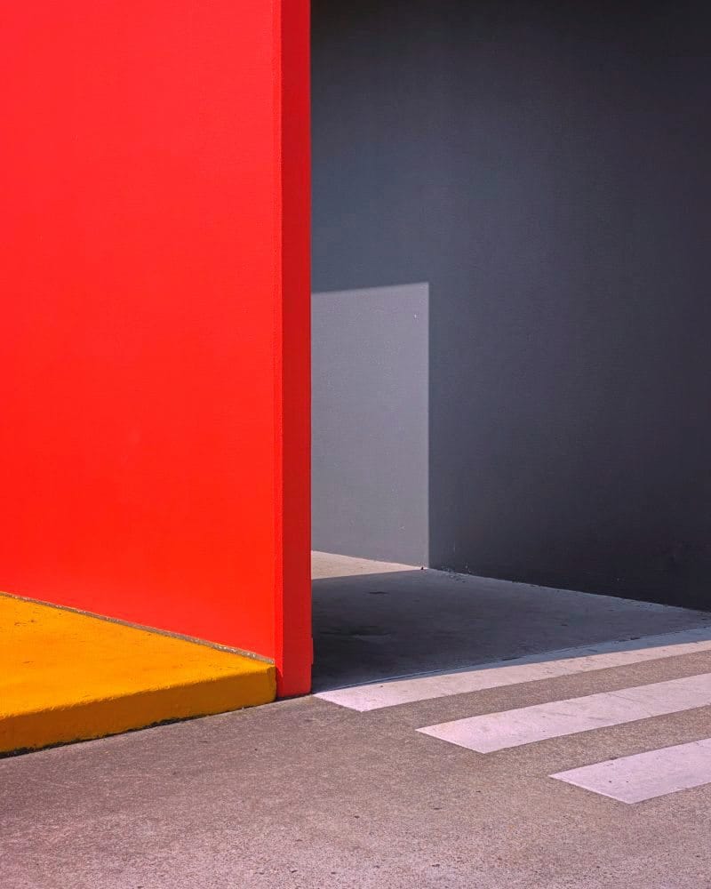 Farbige Platten stehen rechtwinklig zueinander und werfen einen Schatten an die Wand