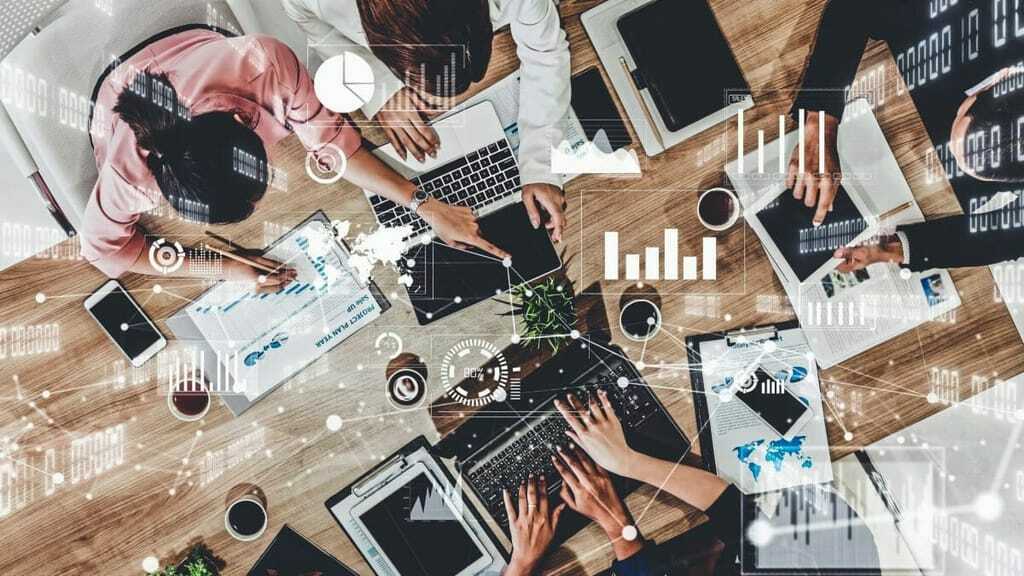 Menschen am Schreibtisch mit Tablets und Laptops