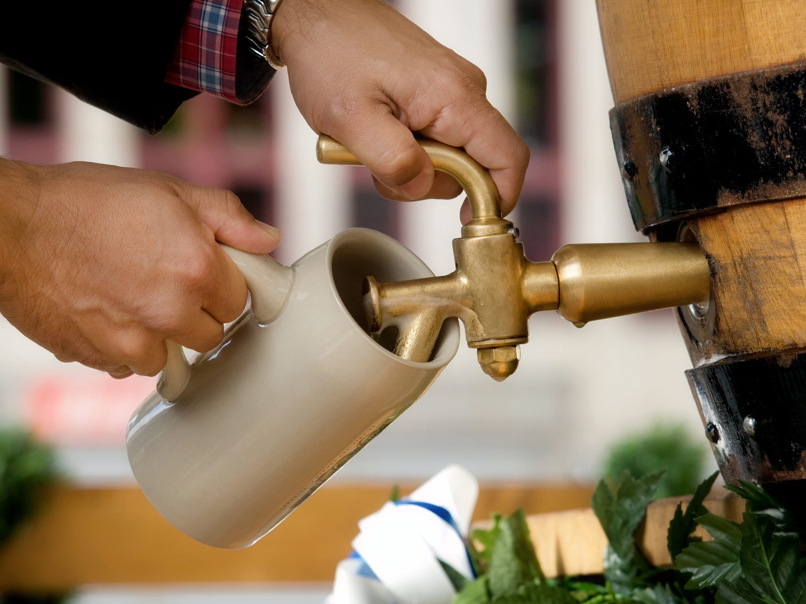 Mann zapft Bier aus Fass in einen Krug