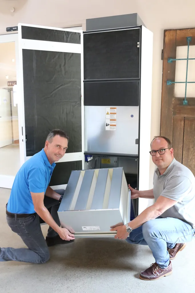 Björn Leutke und sein Onkel Matthias Leutke setzen einen Filter in einen Luftreiniger ein.