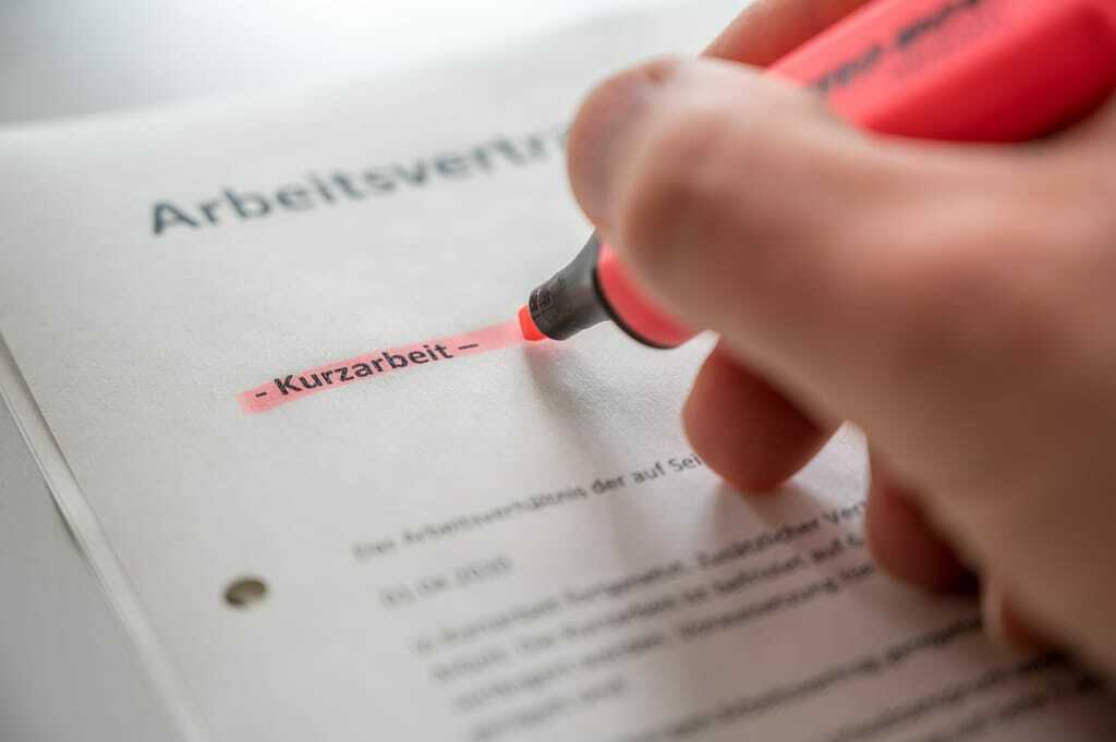Hand markiert mit Stift Wort Kurzarbeit im Arbeitsvertrag.