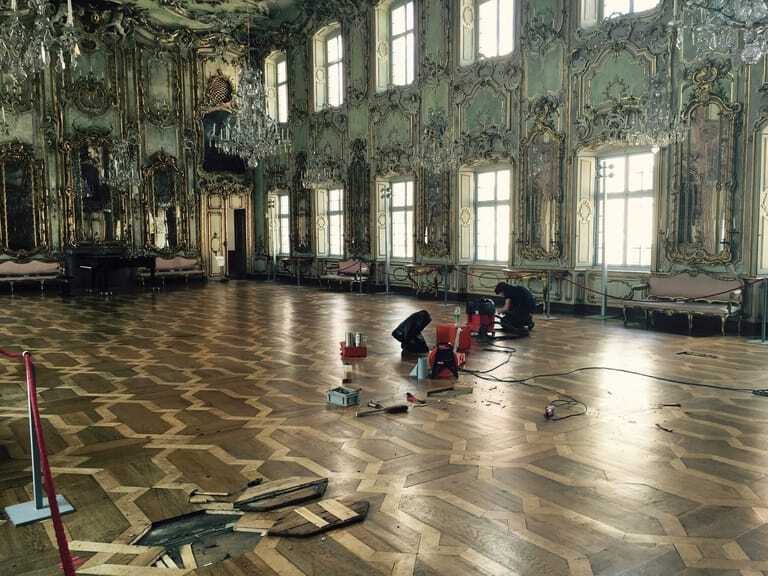 Ein Handwerker restauriert das Parkett in einem historischen Prachtsaal