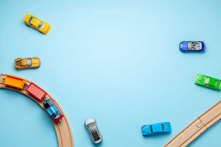 Spielzeug-Autos und -Eisenbahn auf blauem Hintergrund.