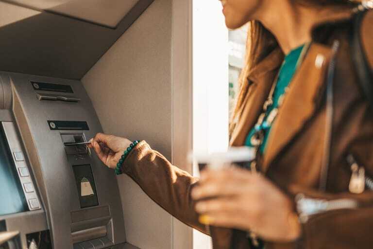 Junge Frau am Bankschalter hebt Geld ab.