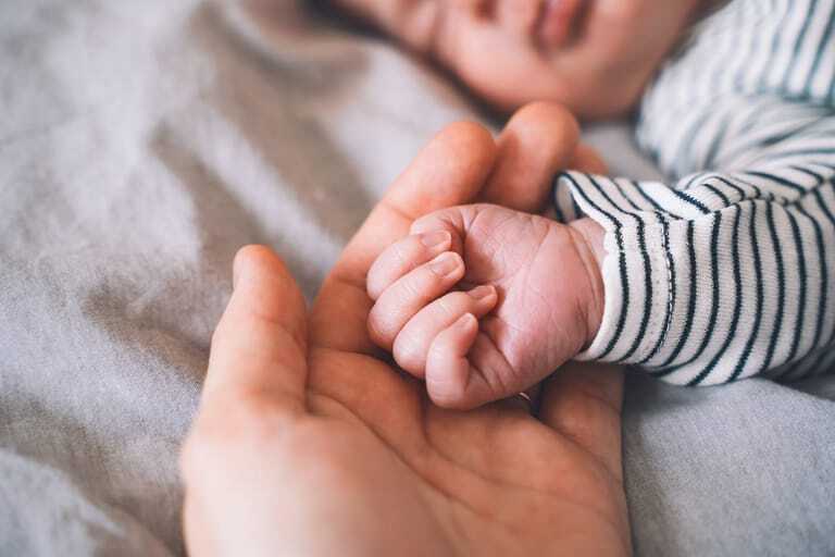 Hand des Vaters hält Hand des Babys.