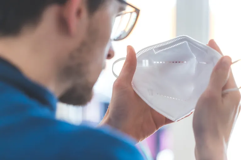 Mann zieht sich FFP-2-Maske an