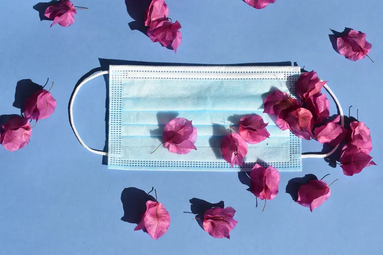 Medizinische Maske mit Blumen auf blauem Hintergrund.