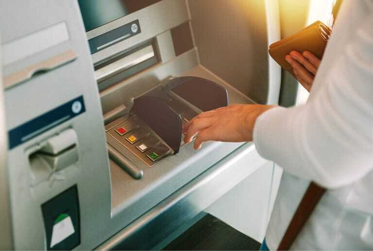 Frau hebt Geld am Bankautomaten ab.