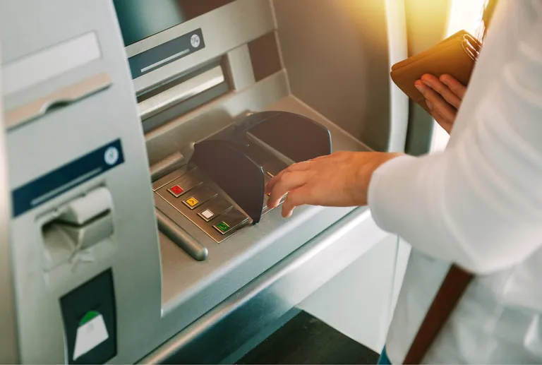 Frau hebt Geld am Bankautomaten ab.