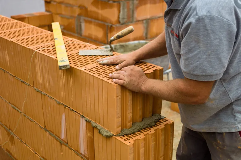 Bauarbeiter auf Baustelle errichtet eine Wand aus Ziegel.