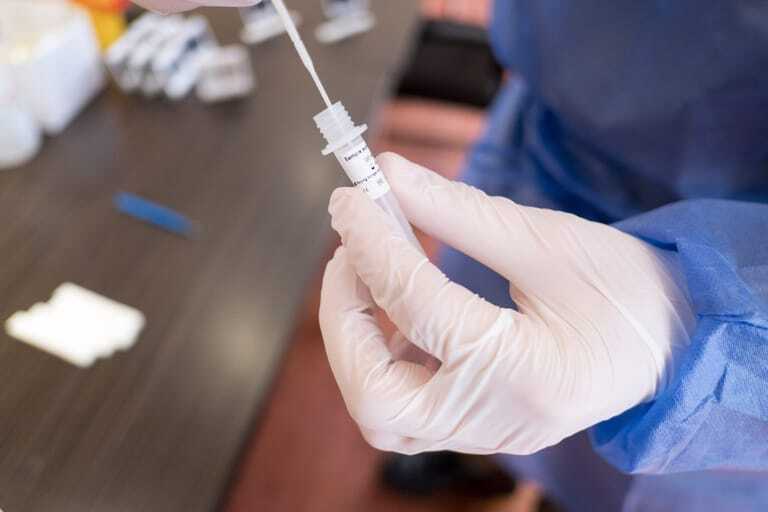 Nahansicht eines PCR-Tests in behandschuhter Hand.