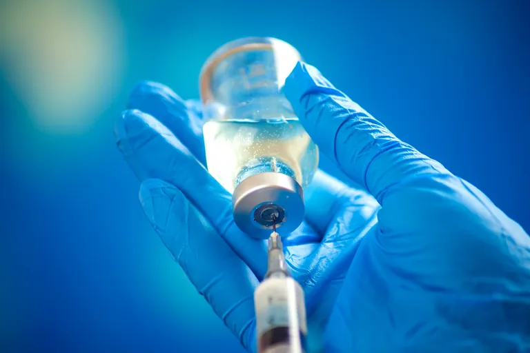 Hand f&uuml;llt Corona-Impfstoff in Spritze.