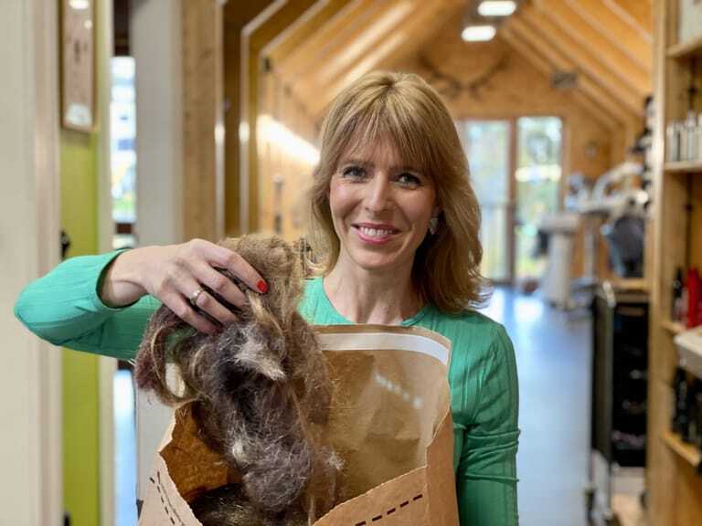 Friseurmeisterin Katja Fischer sammelt abgeschnittene Haare in eine Papiertüte.