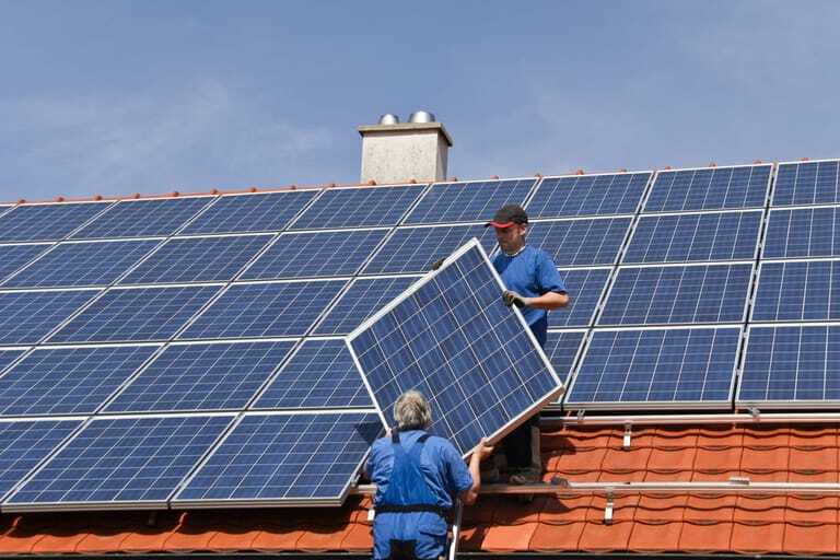 Zwei Handwerker montieren Photovoltaik auf Dach.