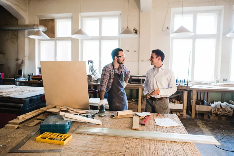 Chef und Mitarbeiter unterhalten sich in der Tischlerei.