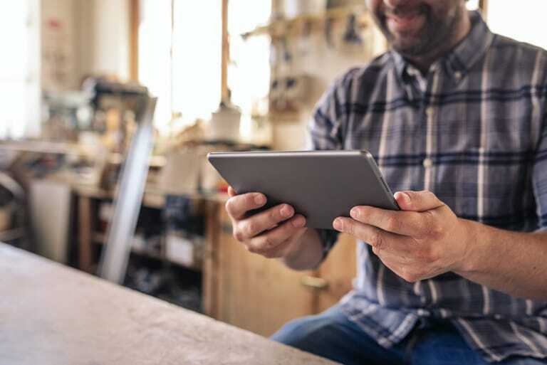 Mann in Werkstatt schaut auf Tablet-PC.