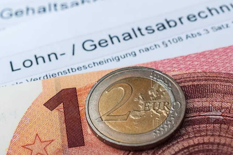 10-Euro-Schein und 2-Euro-Münze auf Gehaltsabrechnung.