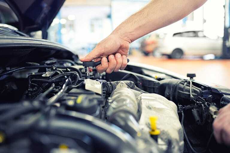 Kfz-Mechaniker repariert Motor in Werkstatt.