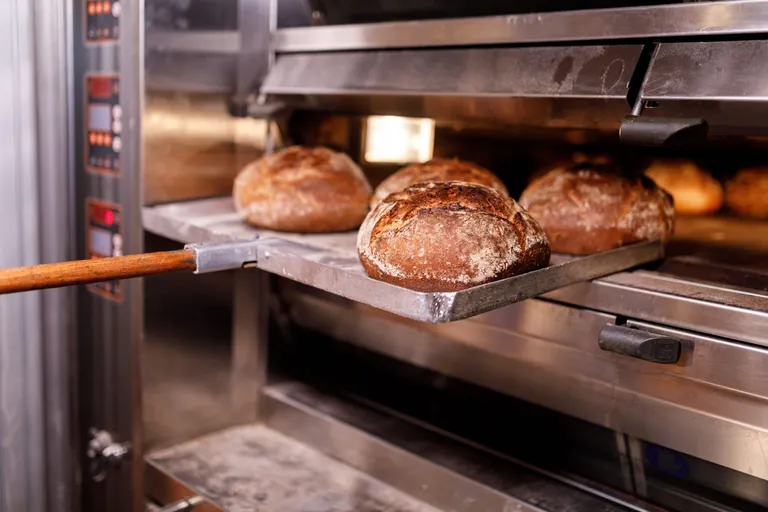 B&Auml;cker holt Brot aus dem Ofen