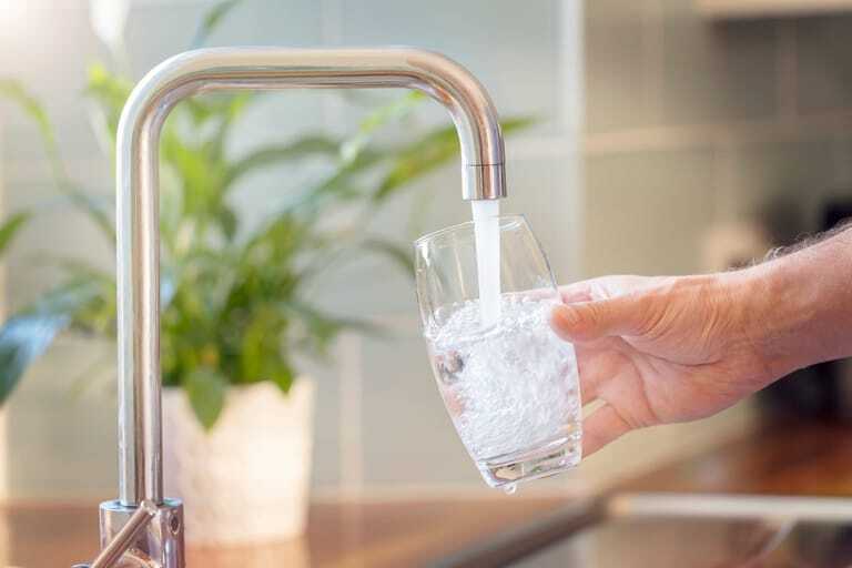 Glas wird mit Wasser aus Hahn gefüllt