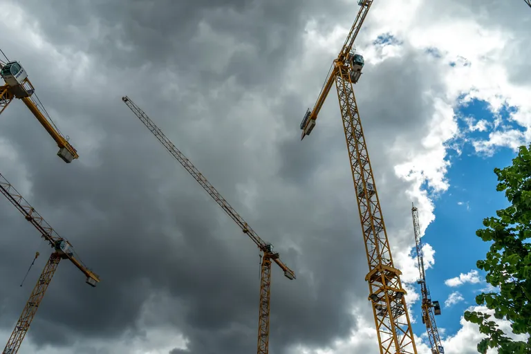 Zwei Baukr&auml;ne &uuml;ber Berlin an Baustellen mit dunklen Wolken.