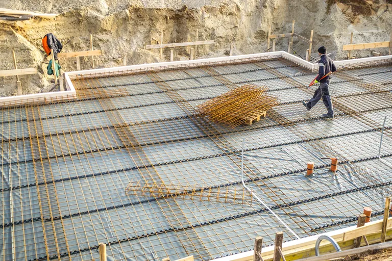 Handwerker verlegen Bodenplatten im Kellergeschoss, Neubau.
