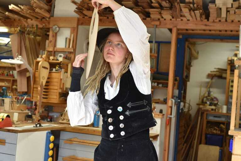 Gitarrenbauerin prüft den Klang des Holzes
