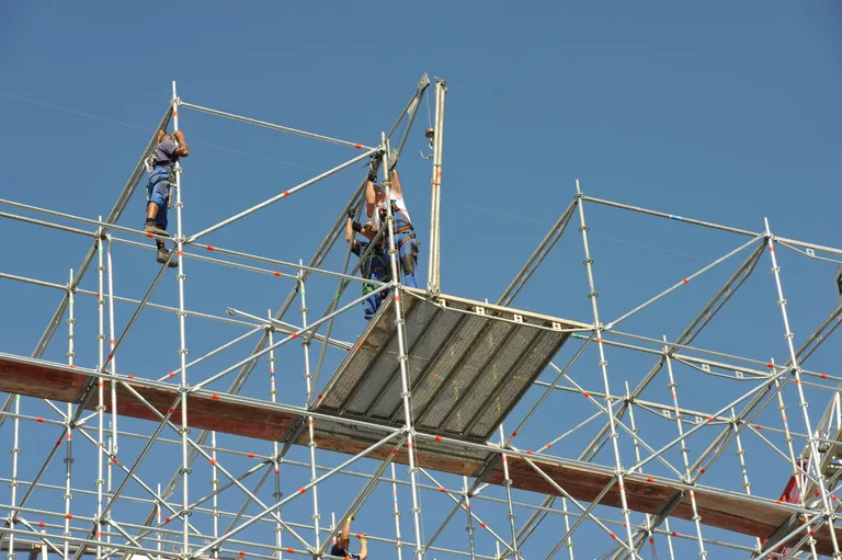 Ger&uuml;stbauer bei der Arbeit auf Ger&uuml;st. Ansicht von unten.
