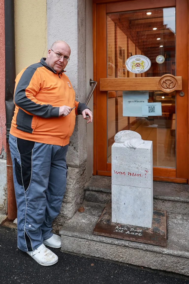 Andreas Rother vor dem Eingang seiner Bäckerei mit einem Grabstein.