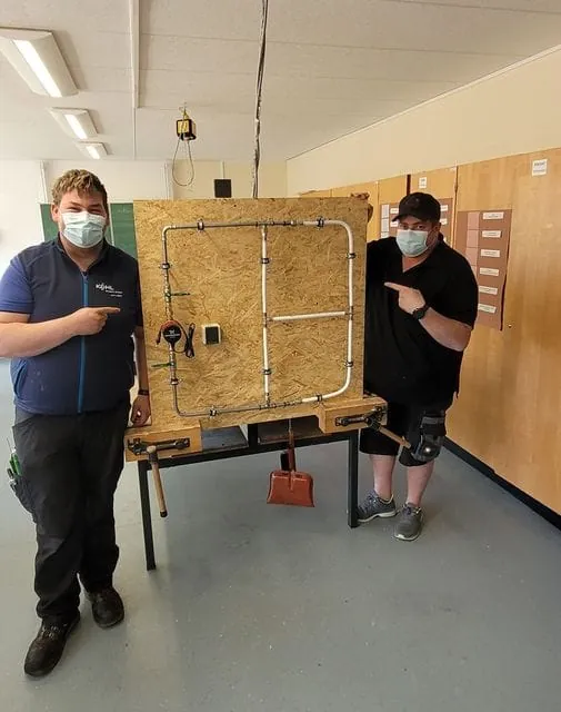 Zwei Mitarbeiter von Kohl Wasser Wärme stehen in einem Klassenzimmer.