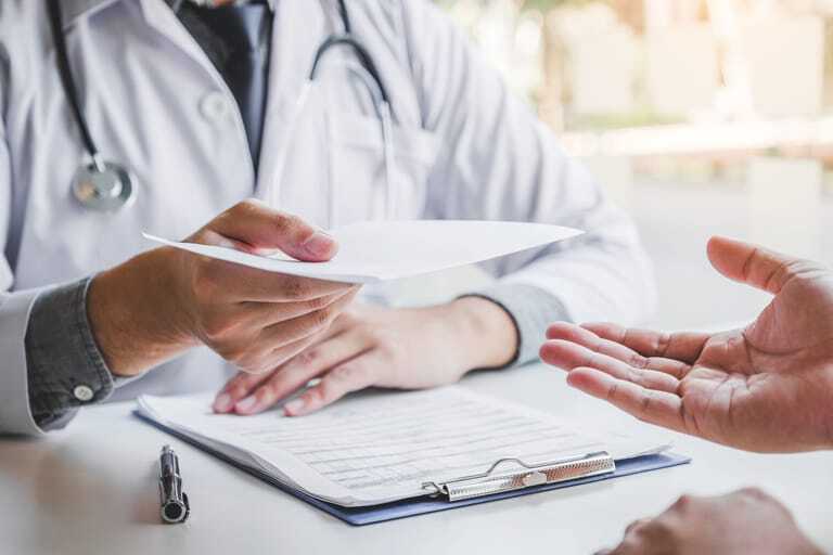 Doktor übergibt Rezept an Patient.