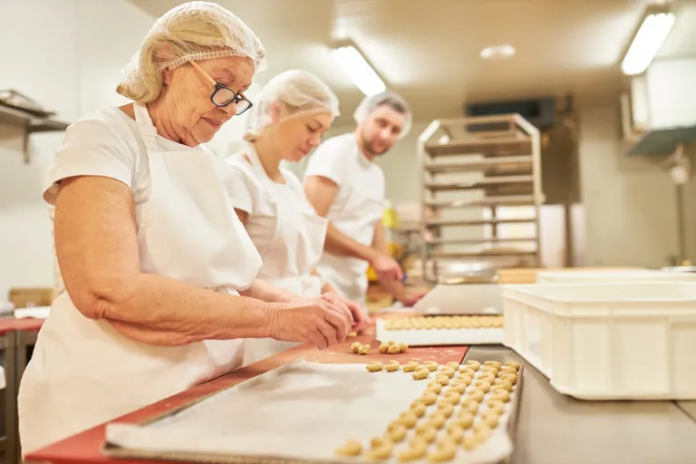 Familie in B&auml;ckerei backt Vanillekipferl.