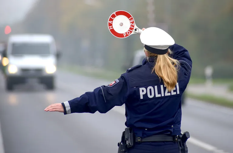 Polizistin mit Kelle bei der Fahrzeugkontrolle