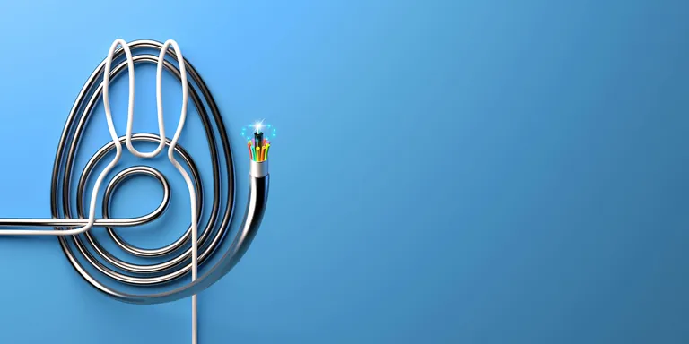 IT-Kabel in Form von Ei und Osterhasen auf blauem Hintergrund gelegt.