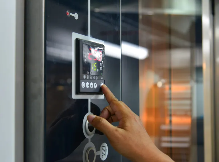 Hand tippt auf Bedienfl&auml;che eines elektrischen Ofens in der B&auml;ckerei.