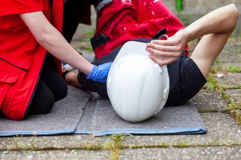 Gestürzter Bauarbeiter bekommt Erste Hilfe.