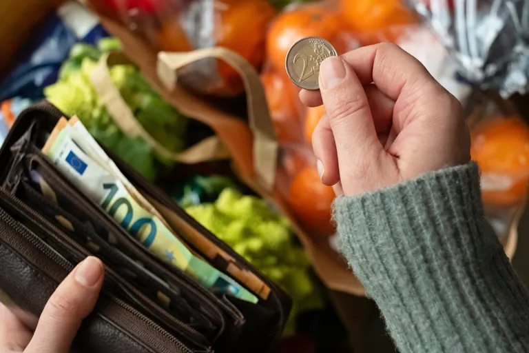 Hand nimmt Geld im Supermarkt aus Geldbörse.