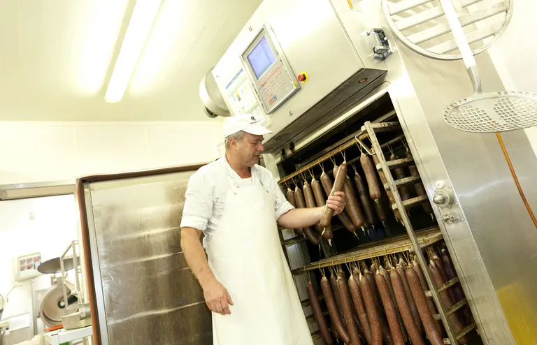 Metzger steht vor seinem Ofen voller Würste