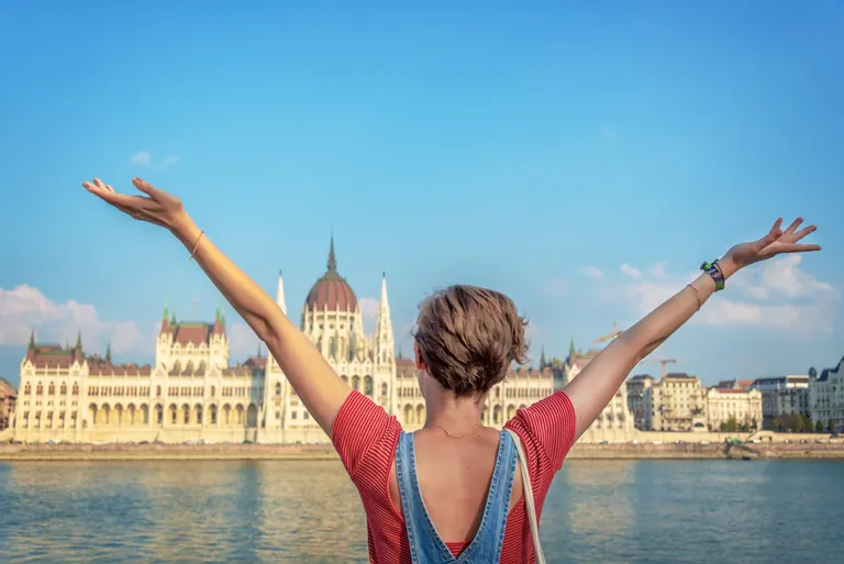 Frau hebt Hände vorm Parlamentsgebäude in Budapest.