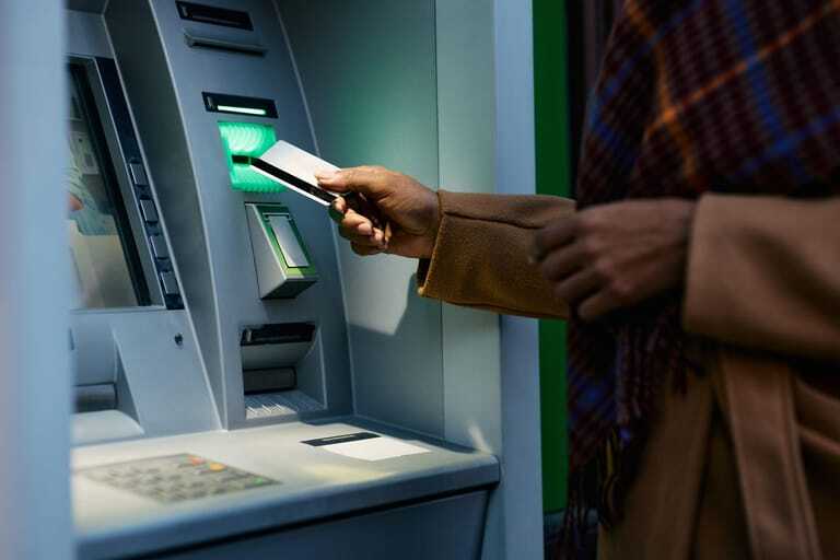 Frau hebt Geld an Automaten ab.