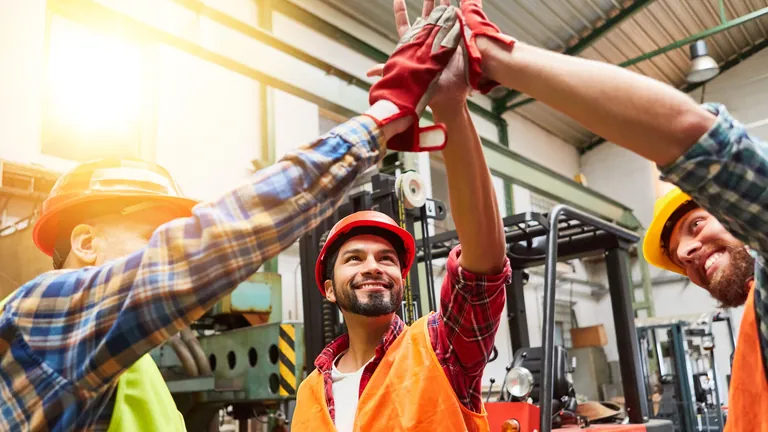 Drei Handwerker klatschen sich ab.