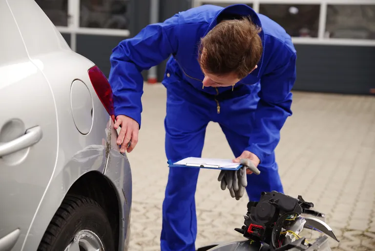 Gutachter inspiziert ein Auto mit Unfallschaden.