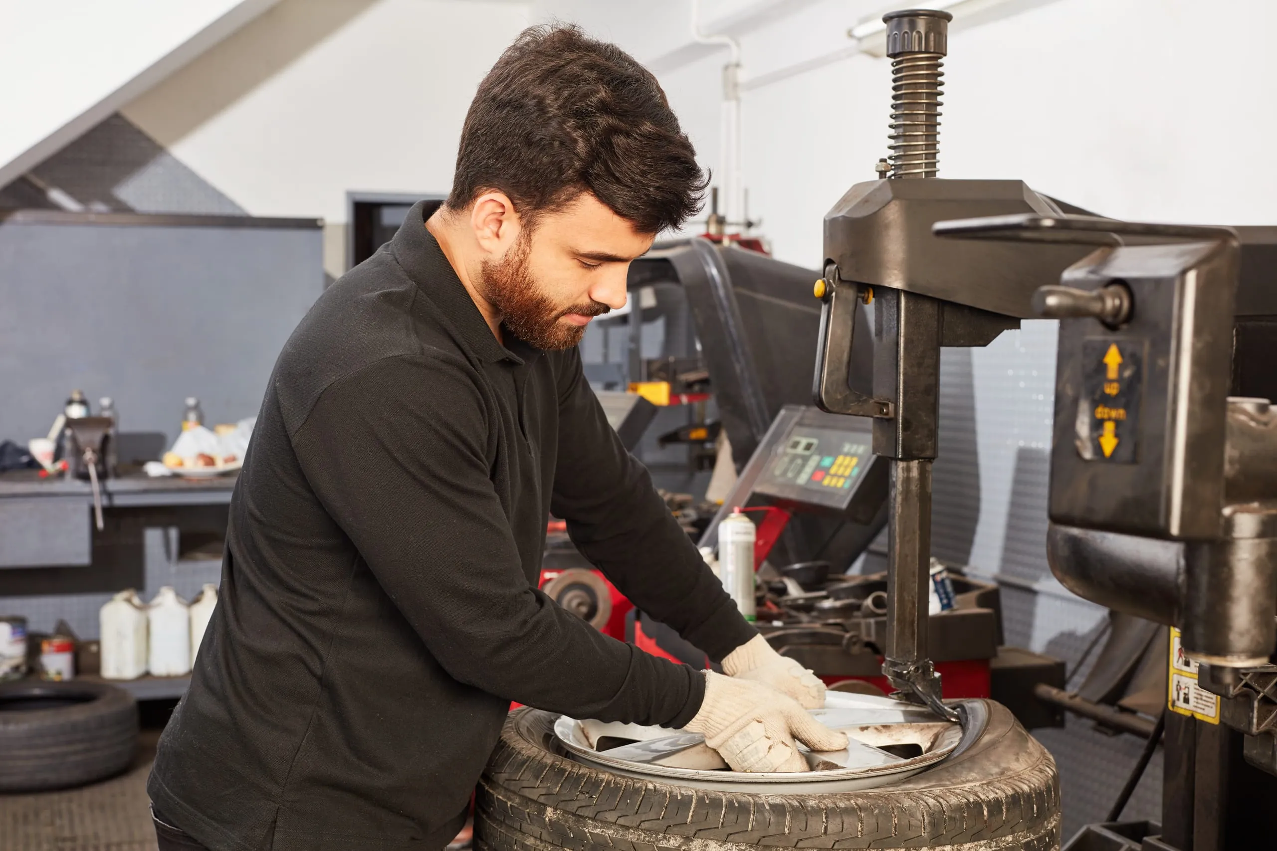 Automechaniker bei Reifenmontage in Werkstatt.