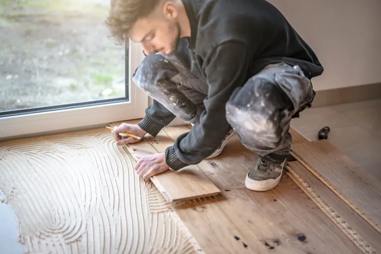 Handwerker verlegt Parkettboden.
